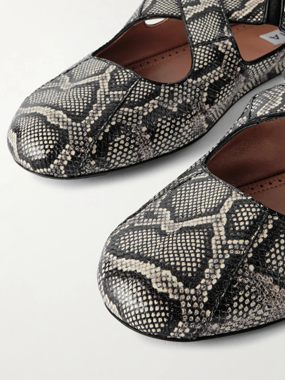 Close-up detail of the Alaïa Criss Cross Leather-trimmed Snakeskin Ballet Flats
