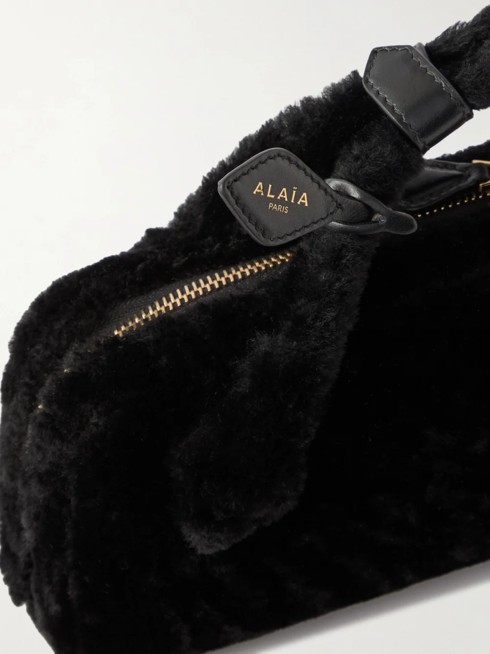 Close-up detail of the Alaïa Le Teckel Leather-trimmed Shearling Clutch