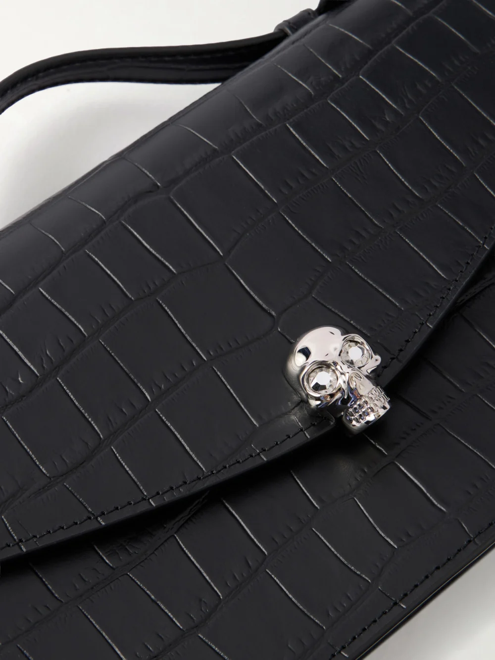 Close-up detail of the Alexander McQueen Skull Embellished Croc-effect Leather Clutch