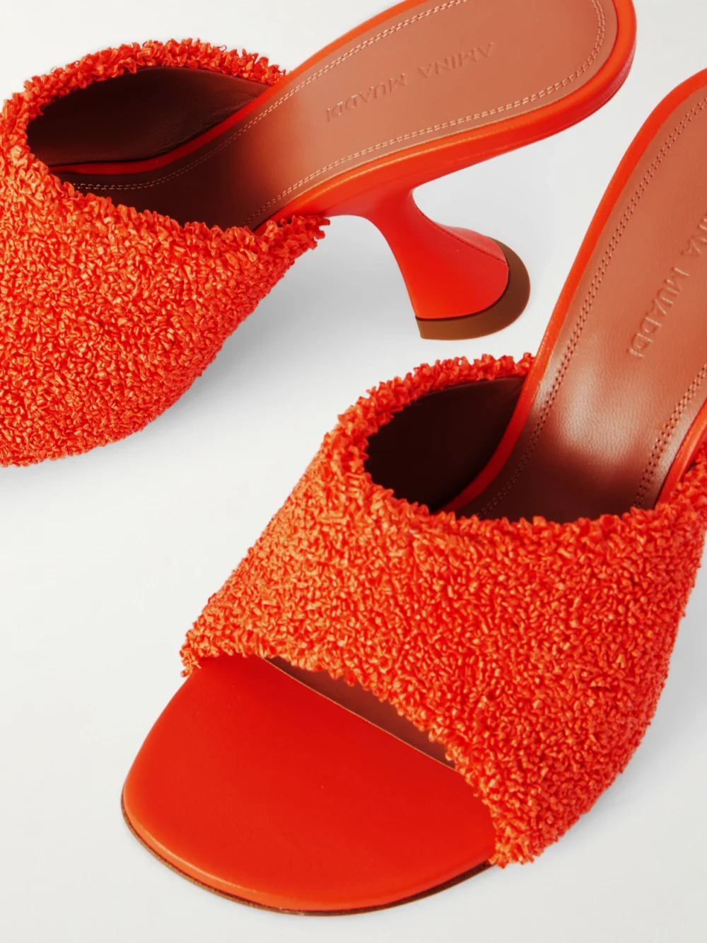 Close-up detail of the Amina Muaddi Taylor Leather-trimmed Raffia Mules