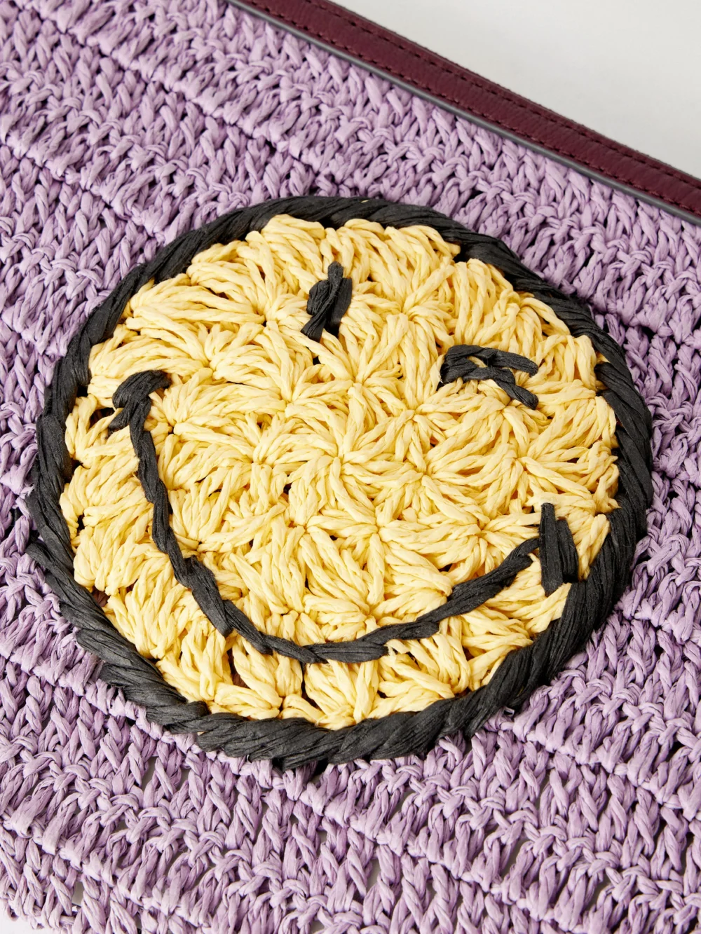 Close-up detail of the Anya Hindmarch Wink Tasseled Leather-trimmed Raffia Clutch Bag