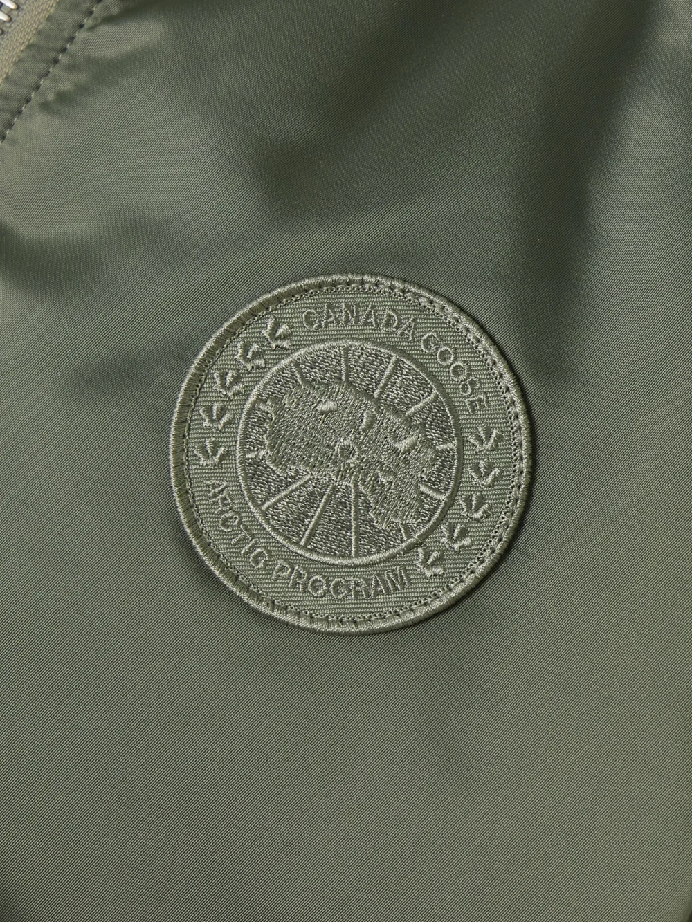 Close-up detail of the Canada Goose Jade Appliquéd Ruched Padded Satin Bomber Jacket