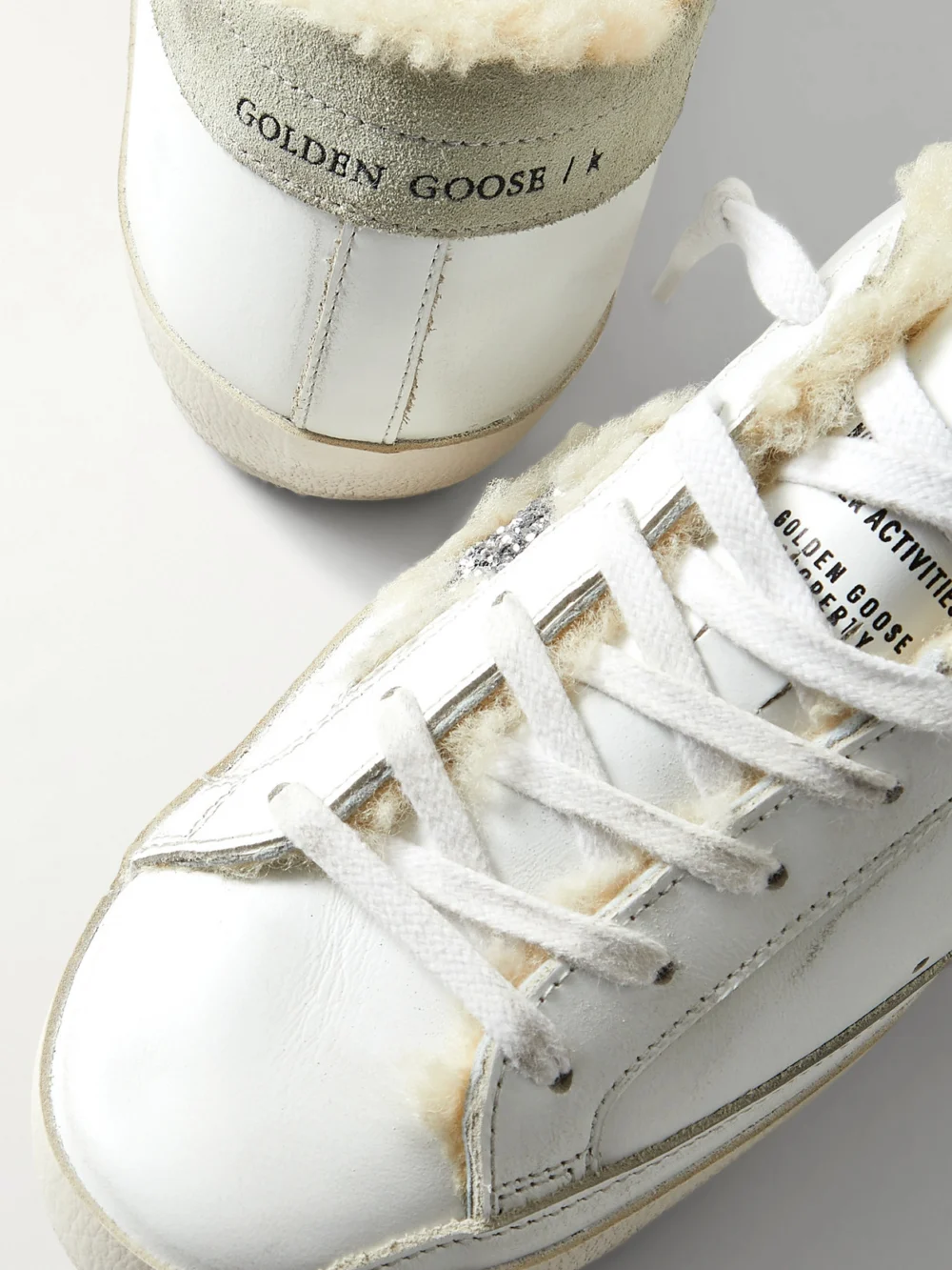 Close-up detail of the Golden Goose Superstar Shearling-lined Distressed Glittered Leather Sneakers