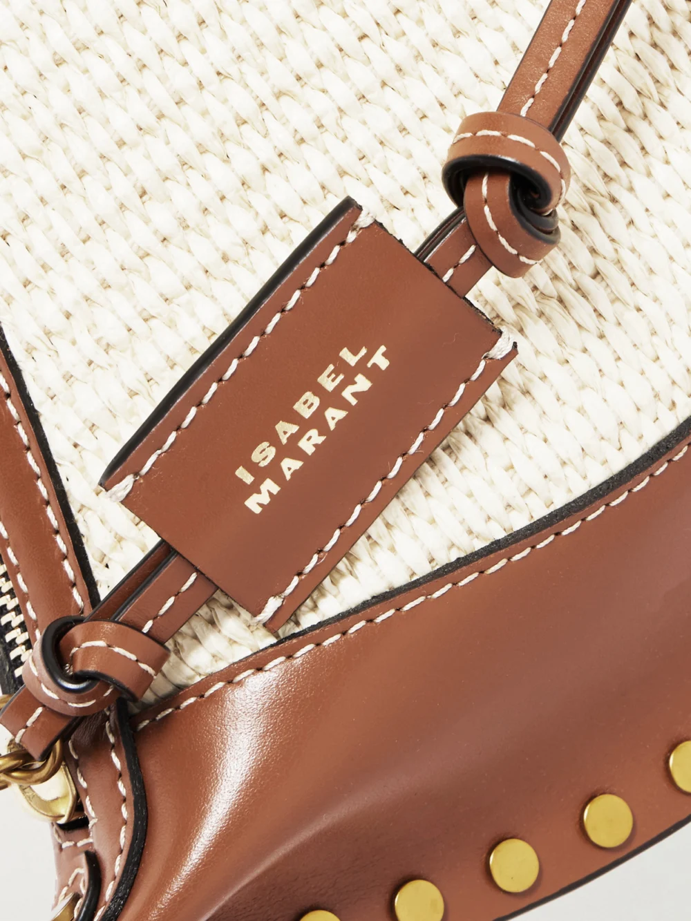 Close-up detail of the Isabel Marant Oskan Moon Studded Leather-trimmed Raffia Shoulder Bag
