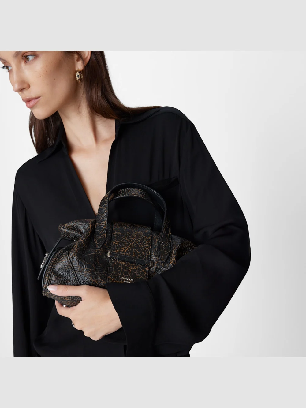 Close-up detail of the Jimmy Choo Bar Holdall Small Black and Toffee Cracked Shiny Leather Holdall Bag
