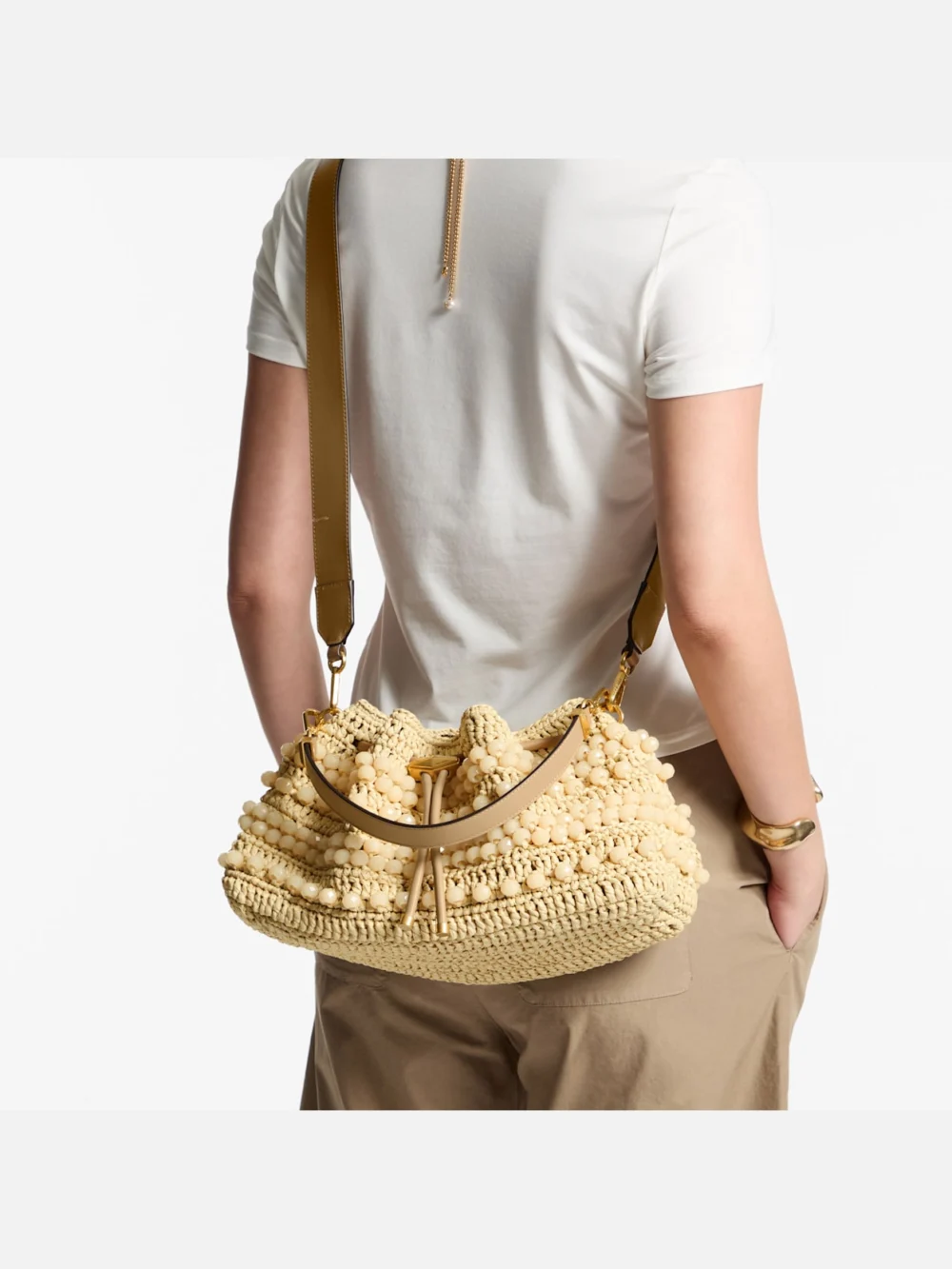 Side view of the Jimmy Choo Cinch Medium Natural and Cappuccino Beaded Raffia Bucket Bag with Smooth Calf Leather
