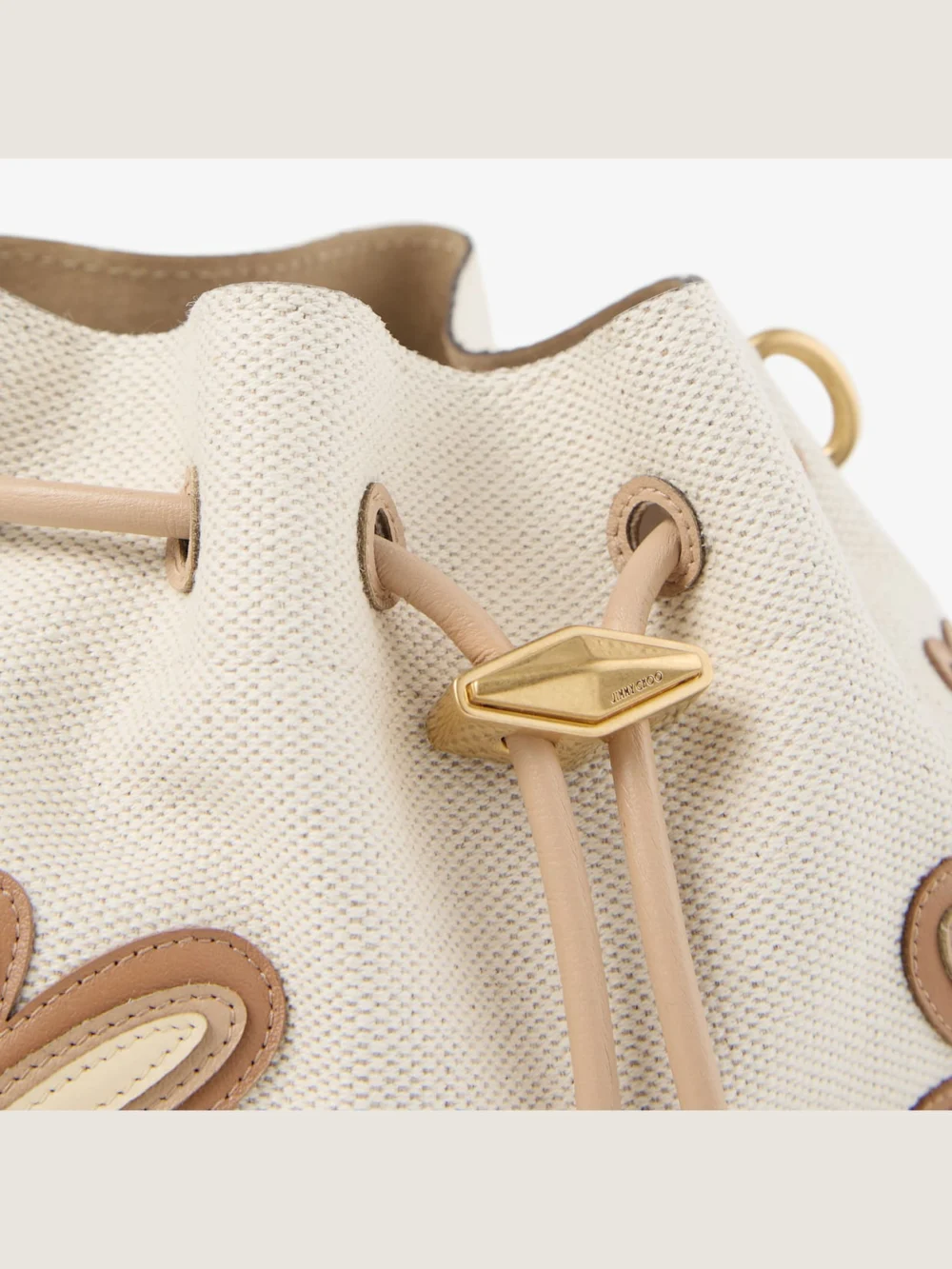 Close-up detail of the Jimmy Choo Cinch Small Natural and Chai Recycled Canvas Shoulder Bag with Intarsia Appliqué
