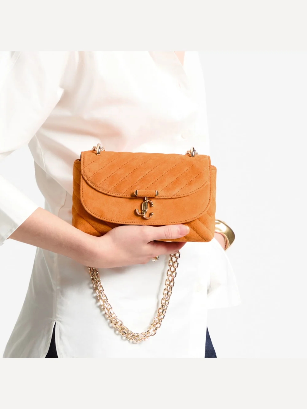 Side view of the Jimmy Choo Curve Crossbody Small Sunset Orange Quilted Suede Crossbody Bag