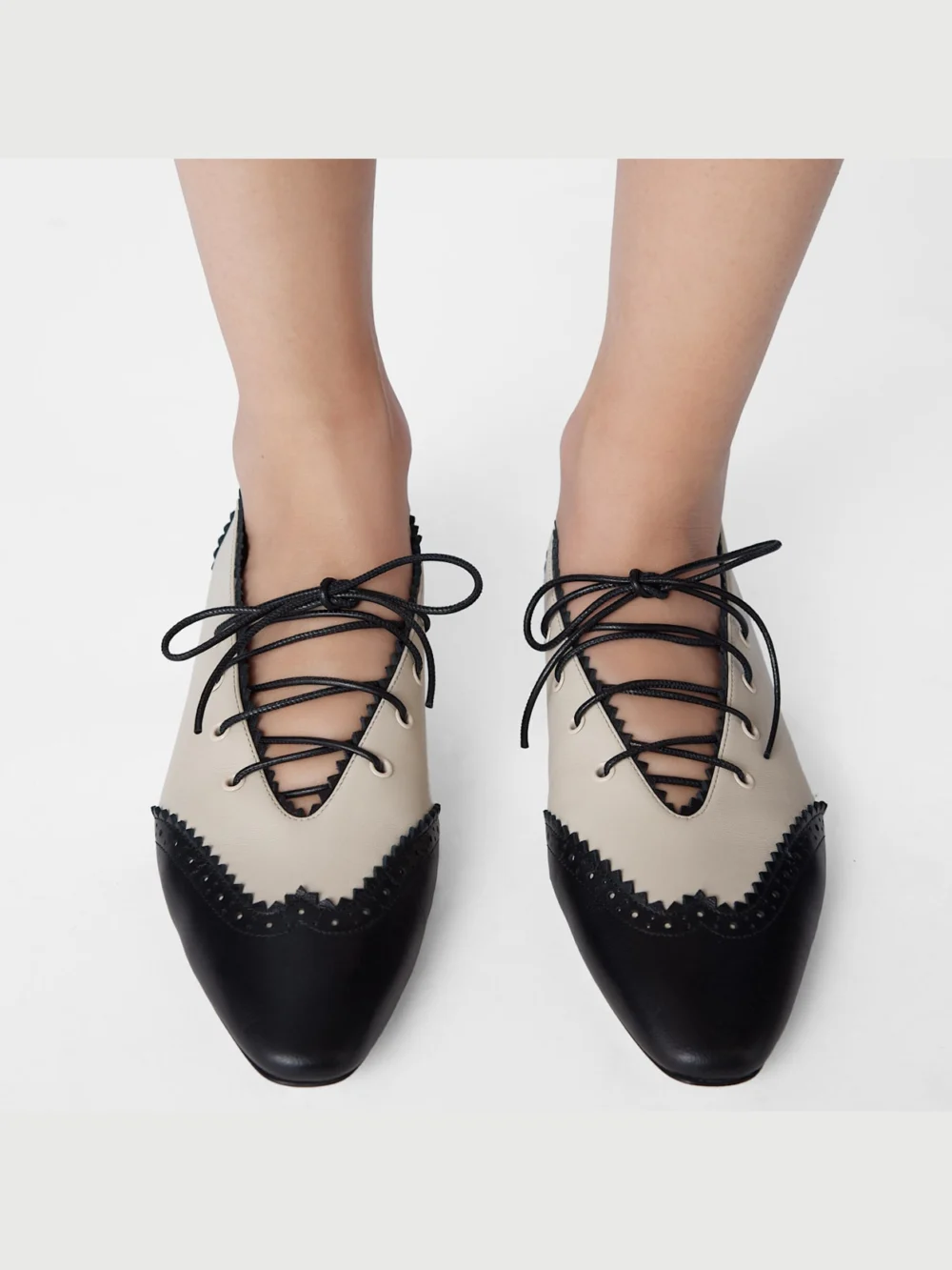 Close-up detail of the Jimmy Choo Margot Lace Up Flat Black and Bone Nappa Leather Lace Up Flats with Broguing