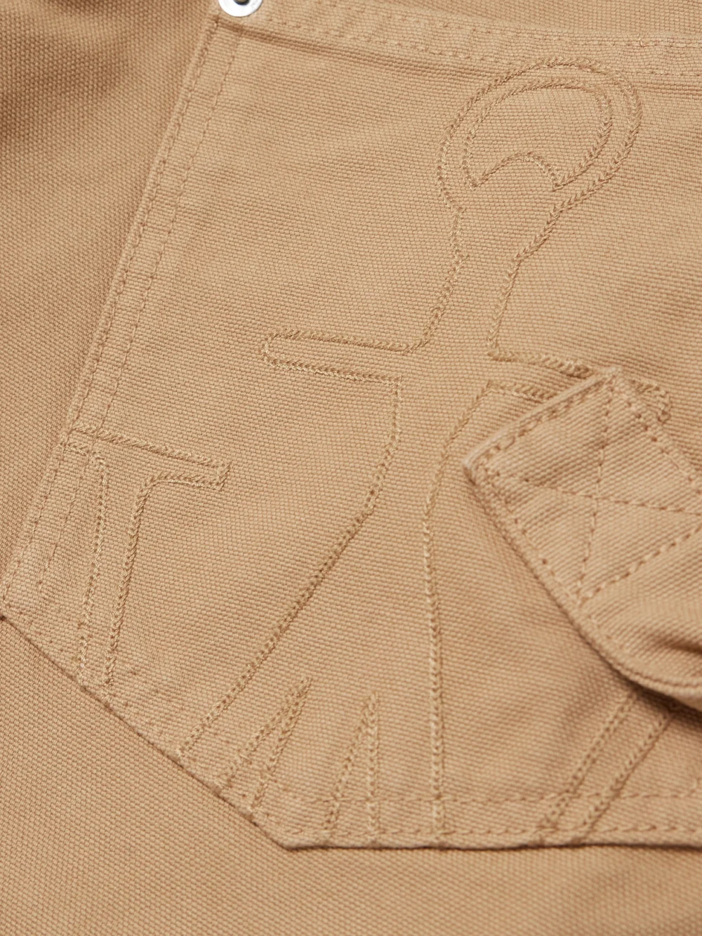 Close-up detail of the JW Anderson Twisted Asymmetric Embroidered Cotton-canvas Pants