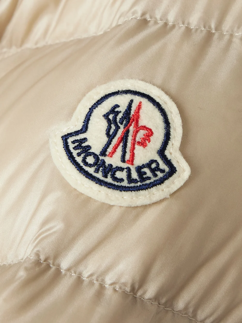 Close-up detail of the Moncler Argenno Hooded Belted Appliquéd Quilted Shell Down Coat