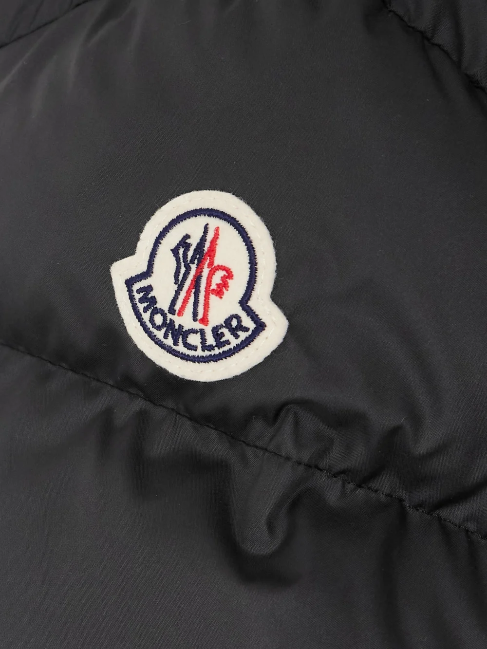 Close-up detail of the Moncler Brosse Belted Hooded Appliquéd Quilted Shell Down Jacket