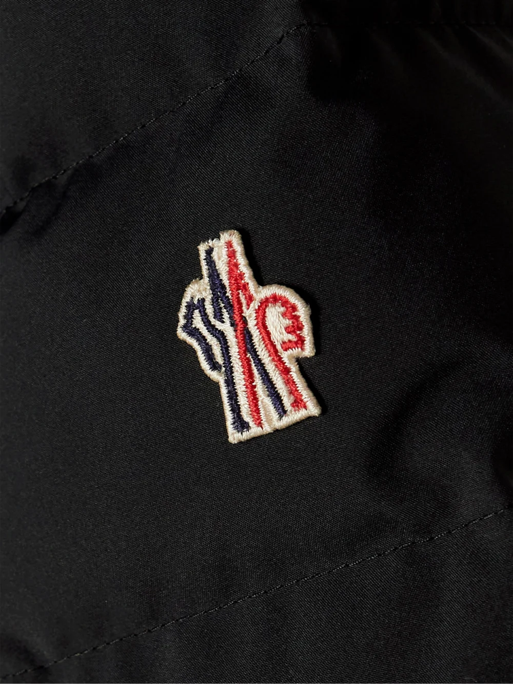 Close-up detail of the Moncler Grenoble Lamoura Hooded Grosgrain-trimmed Quilted Down Ski Jacket