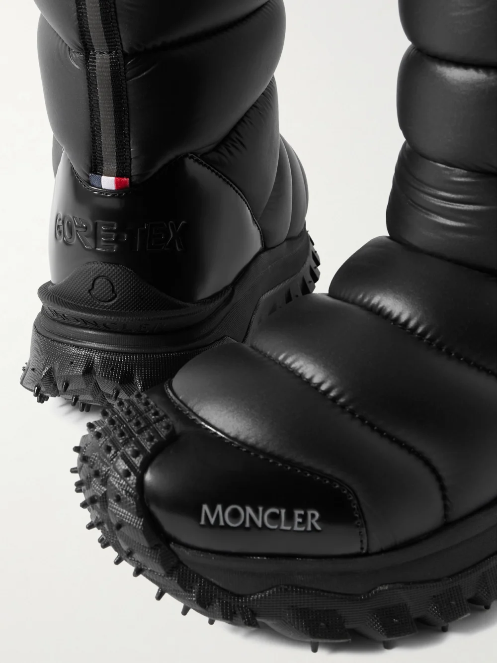 Close-up detail of the Moncler Trailgrip Appliquéd Quilted Padded Glossed Leather-trimmed Shell Snow Boots