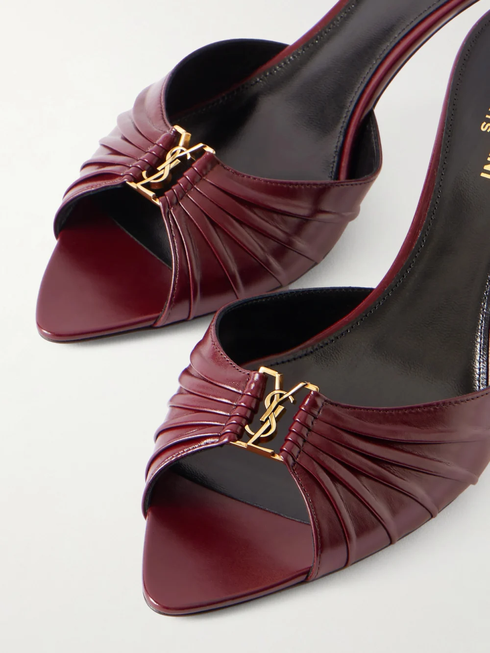 Close-up detail of the Saint Laurent Babylone Cassandre-embellished Gathered Glossed-leather Mules