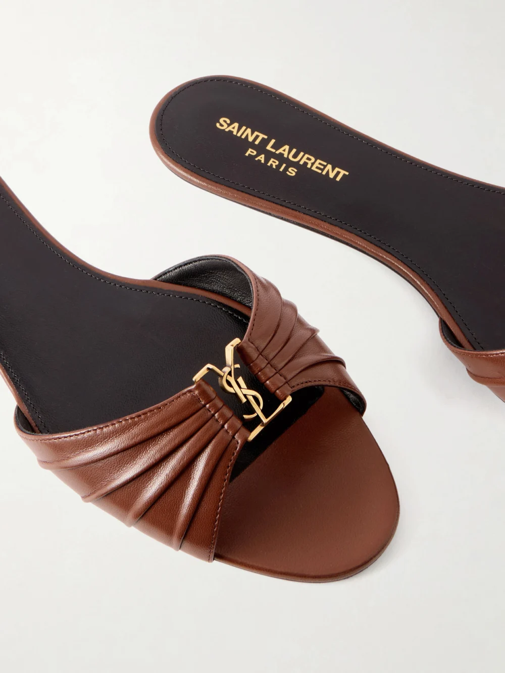 Close-up detail of the Saint Laurent Babylone Cassandre-embellished Gathered Glossed-leather Slides