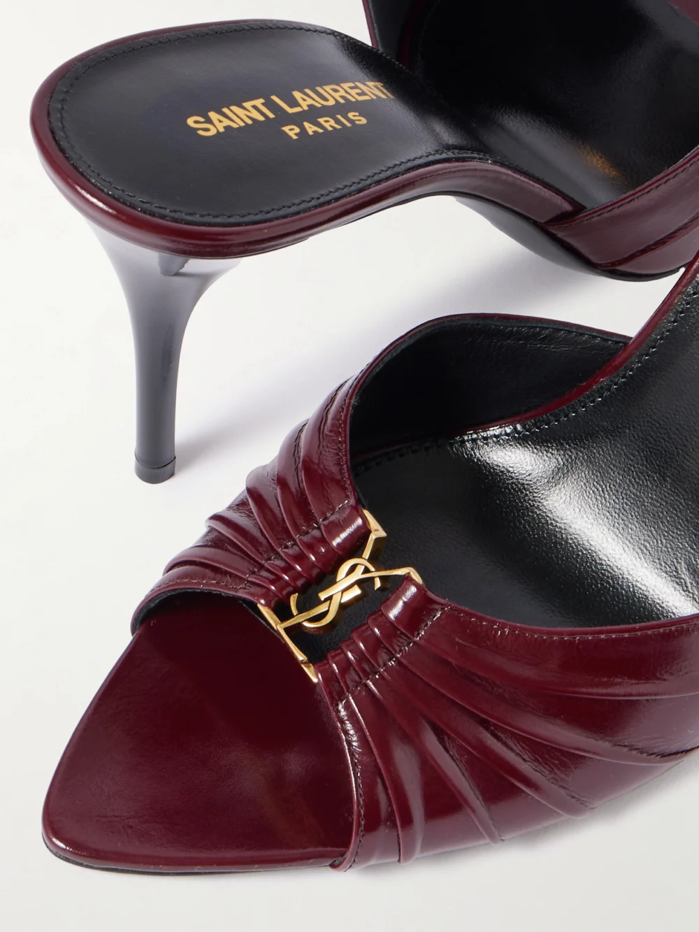 Close-up detail of the Saint Laurent Babylone Cassandre-embellished Gathered Patent-leather Mules
