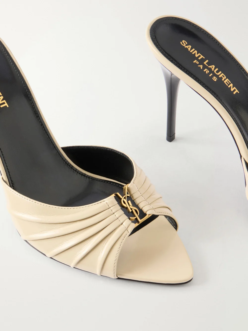 Close-up detail of the Saint Laurent Babylone Cassandre-embellished Gathered Patent-leather Mules