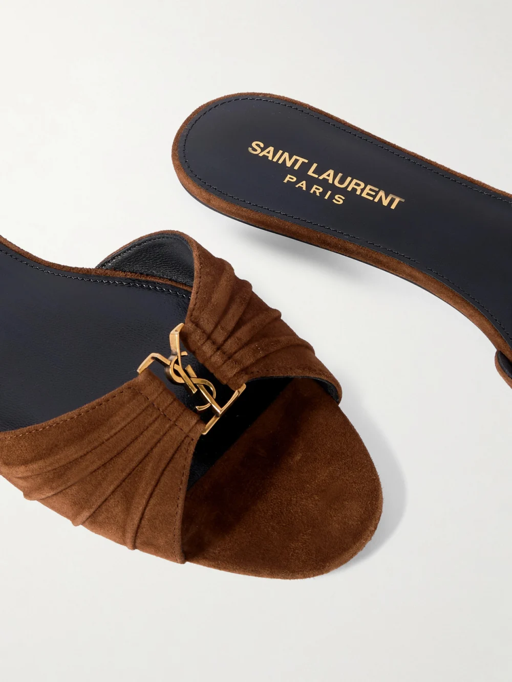 Close-up detail of the Saint Laurent Babylone Cassandre-embellished Gathered Suede Slides