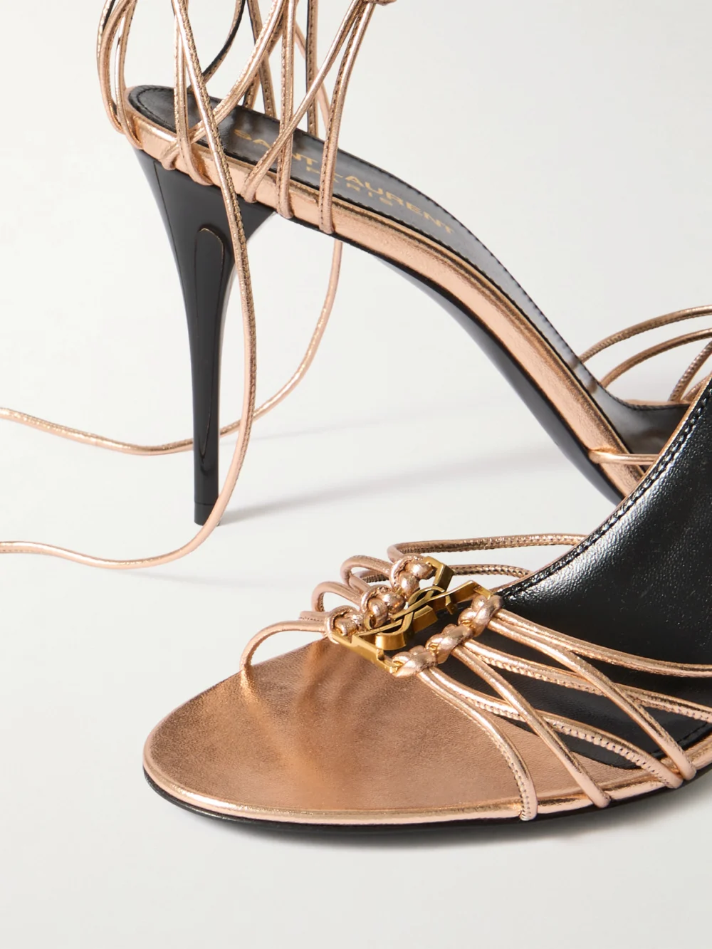 Close-up detail of the Saint Laurent Babylone Cassandre-embellished Knotted Metallic Leather Sandals