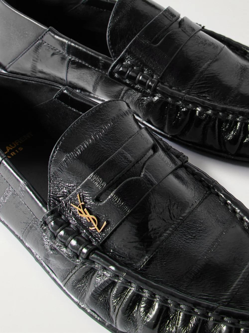 Close-up detail of the Saint Laurent Le Loafer Cassandre-embellished Collapsible-heel Glossed-eel Loafers