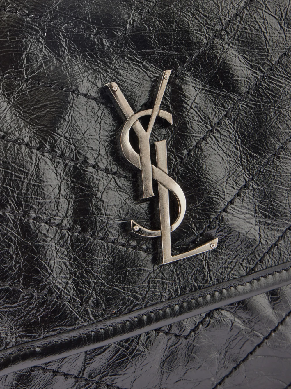Close-up detail of the Saint Laurent Niki Medium Cassandre-embellished Crinkled Glossed-leather Shoulder Bag