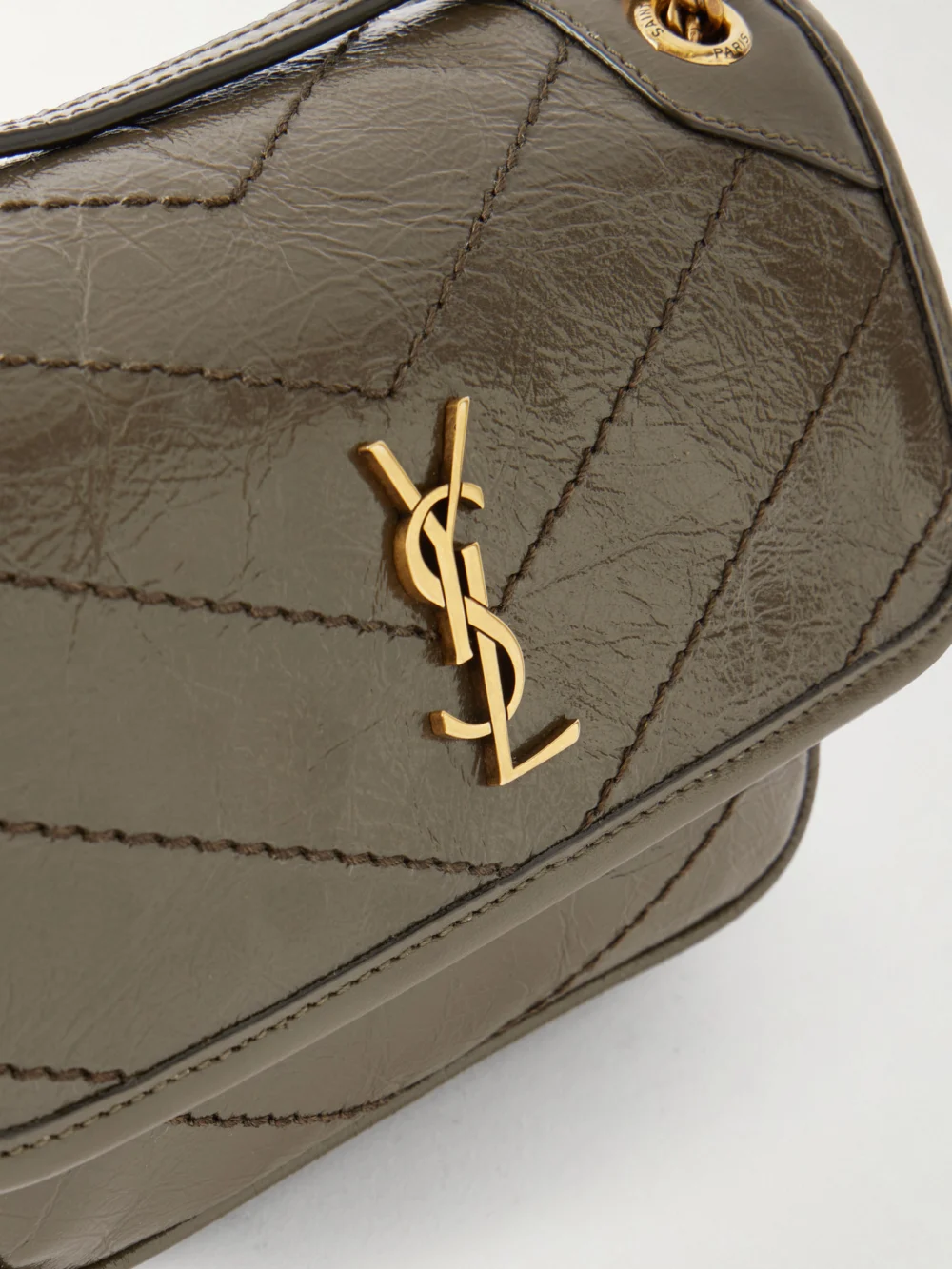 Close-up detail of the Saint Laurent Niki Mini Cassandre-embellished Crinkled-leather Shoulder Bag
