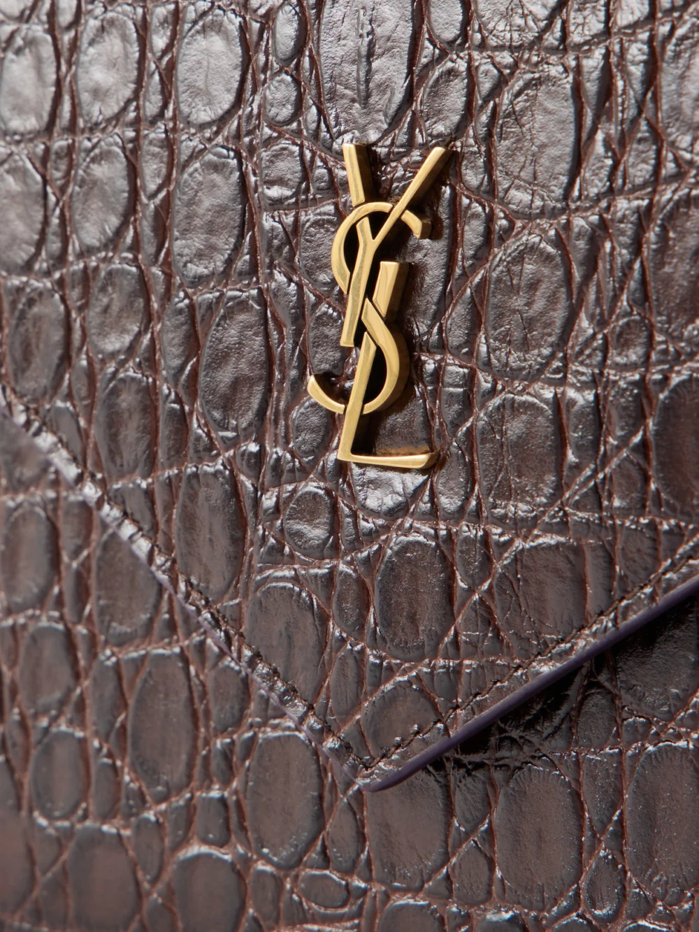 Close-up detail of the Saint Laurent Paris Cassandre-embellished Croc-effect Leather Clutch