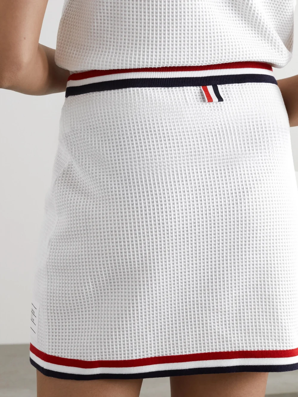 Back view of the Thom Browne Wrap-effect Striped Waffle-knit Cotton Mini Skirt