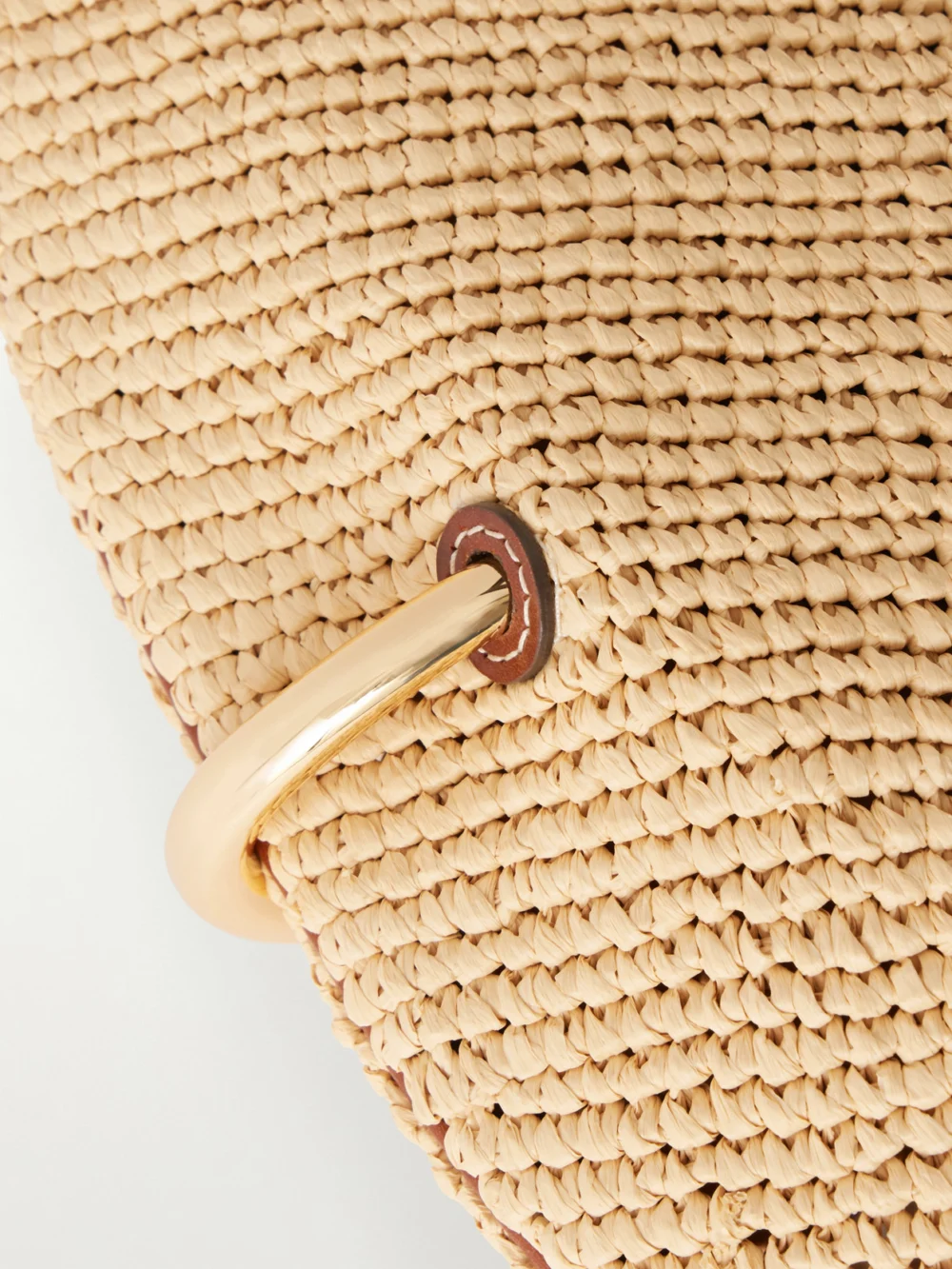 Close-up detail of the Tory Burch Pierced Embellished Leather-trimmed Raffia Shoulder Strap
