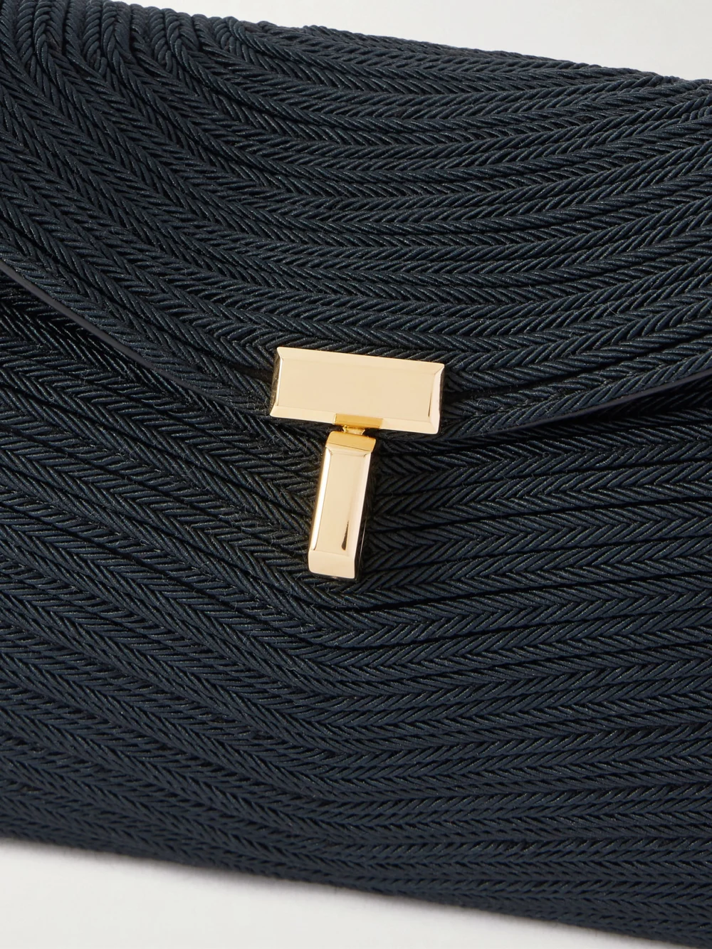 Close-up detail of the Totême Mini T-lock Leather-trimmed Woven Clutch