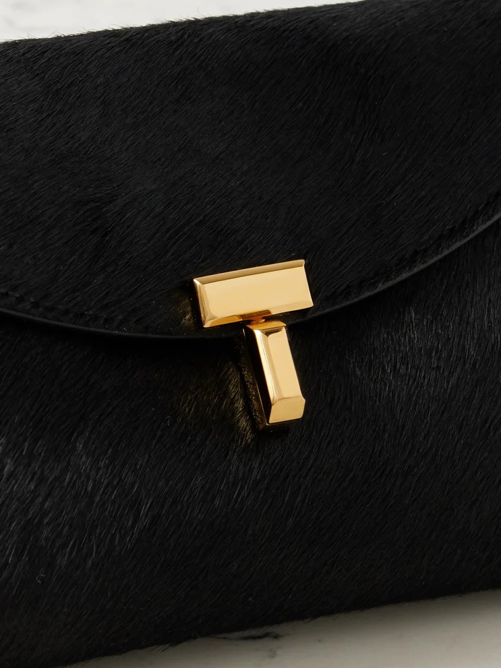 Close-up detail of the Totême T-lock Mini Calf Hair Clutch