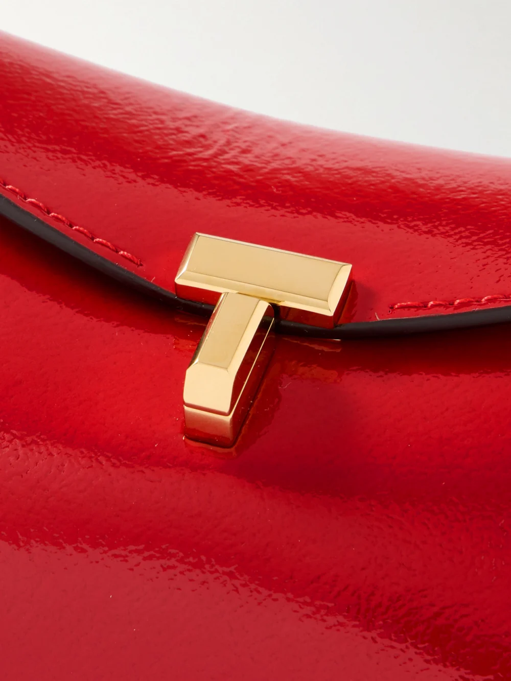 Close-up detail of the Totême T-lock Mini Patent-leather Clutch