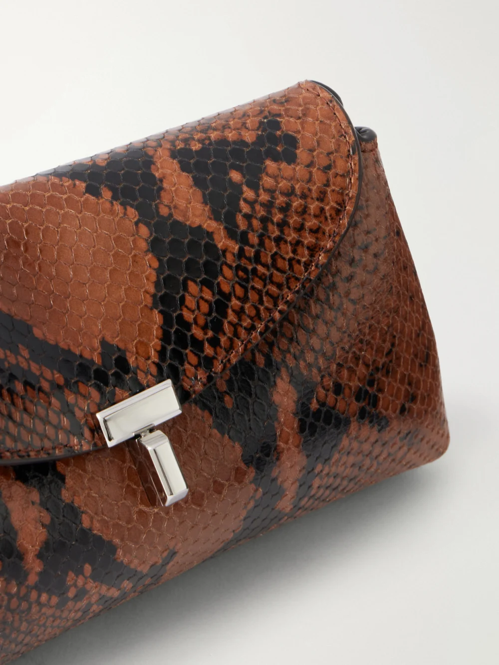 Close-up detail of the Totême T-lock Mini Snake-effect Leather Clutch