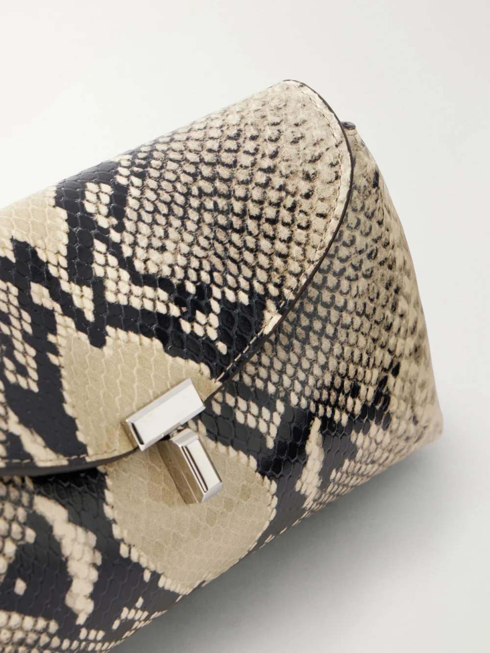 Close-up detail of the Totême T-lock Mini Snake-effect Leather Clutch