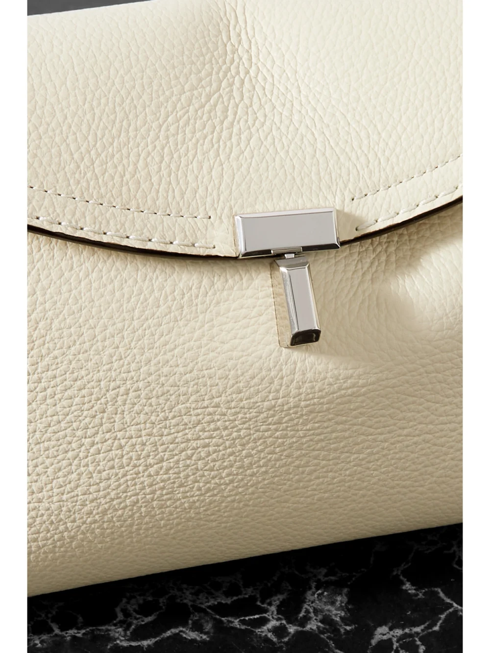 Close-up detail of the Totême T-lock Textured-leather Clutch