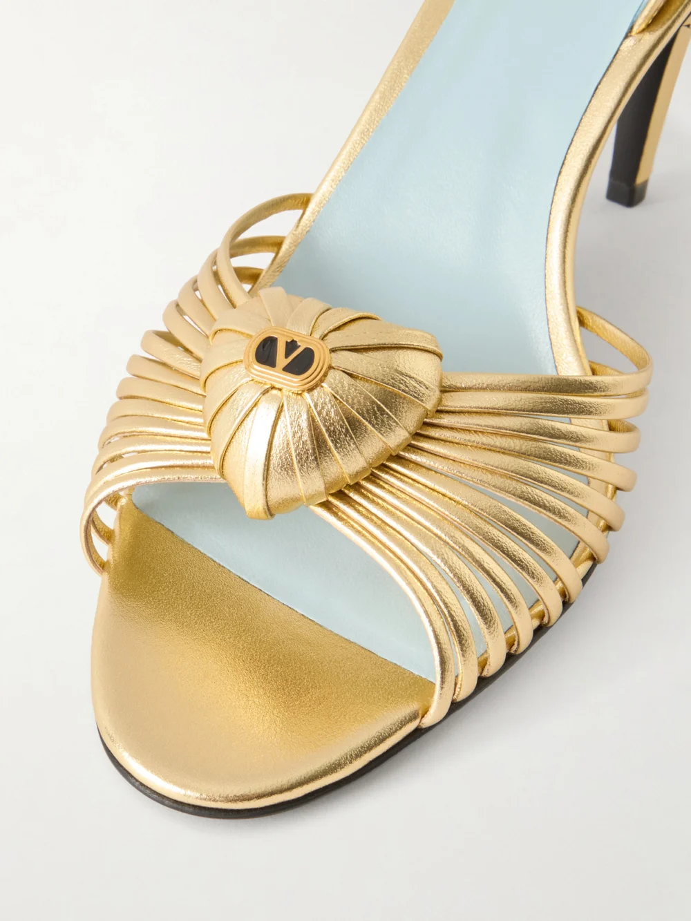 Close-up detail of the Valentino Garavani Coeur Royal 85 Logo-embellished Metallic Leather Sandals