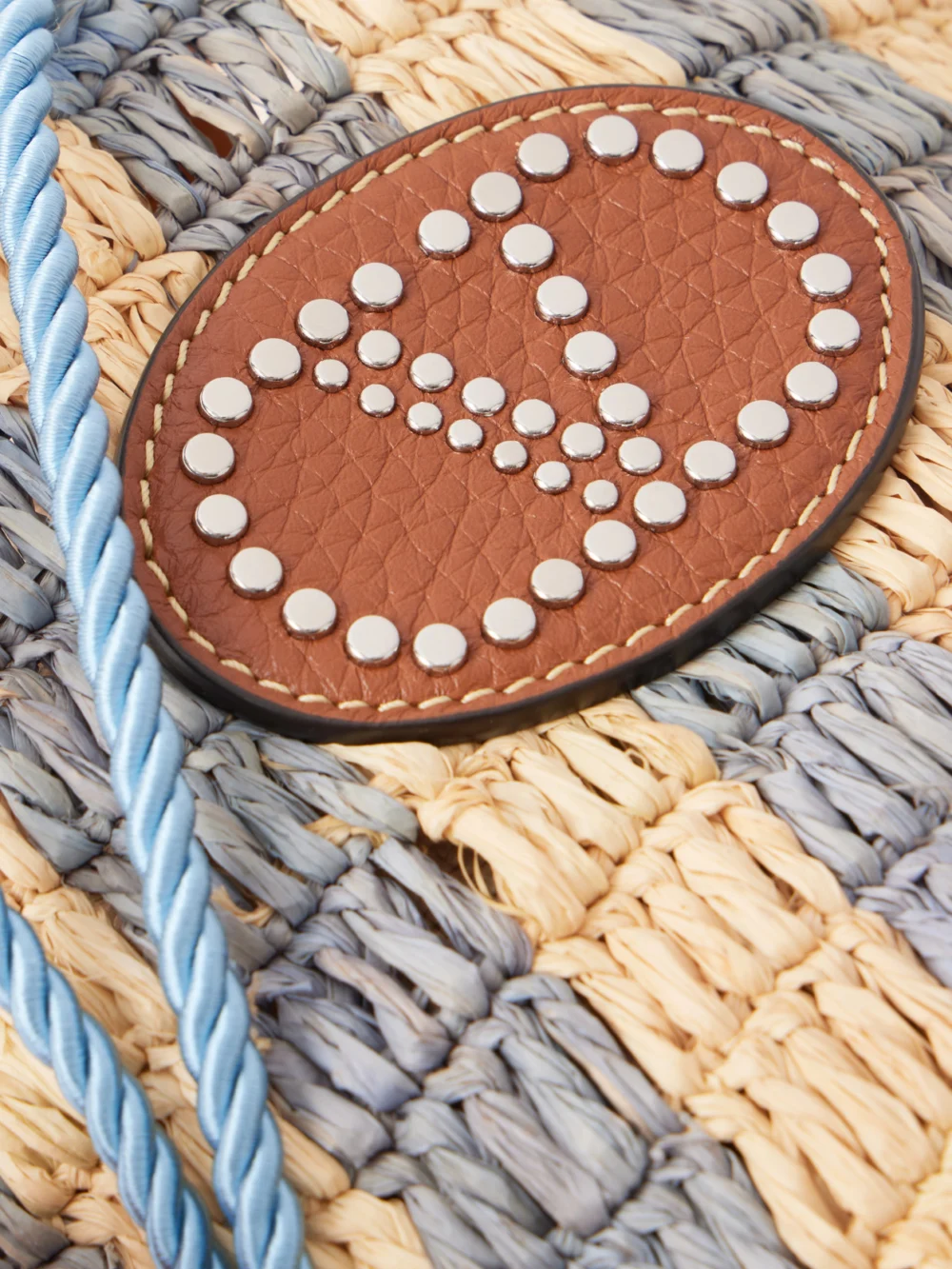 Close-up detail of the Valentino Garavani Embellished Striped Leather-trimmed Raffia Bucket Bag