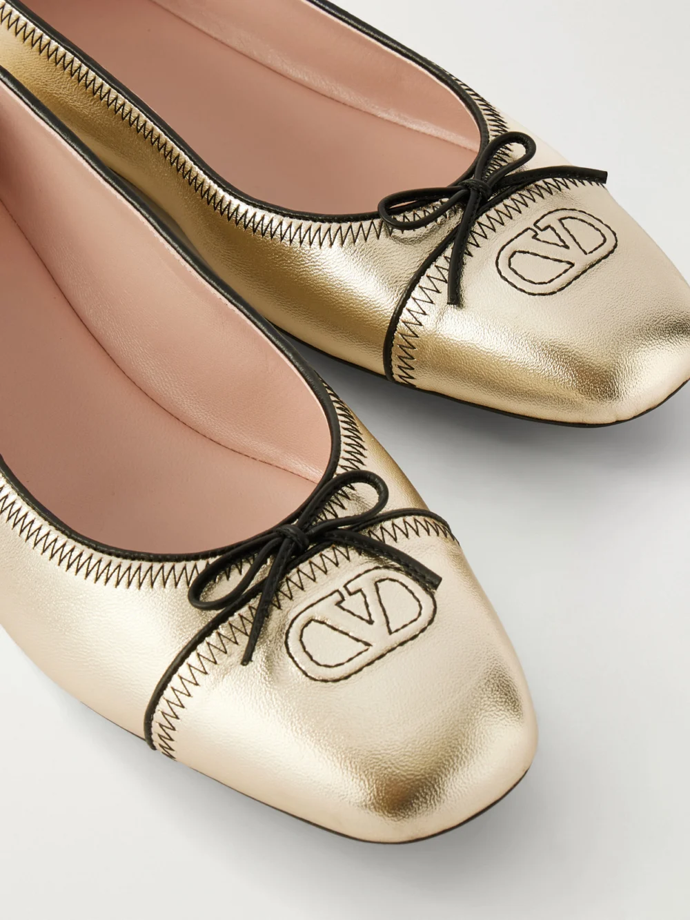 Close-up detail of the Valentino Garavani Vlogo Bow-embellished Metallic Leather Ballet Flats