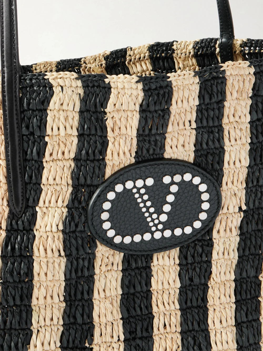 Close-up detail of the Valentino Garavani Vlogo Signature Small Leather-trimmed Striped Raffia Bucket Bag