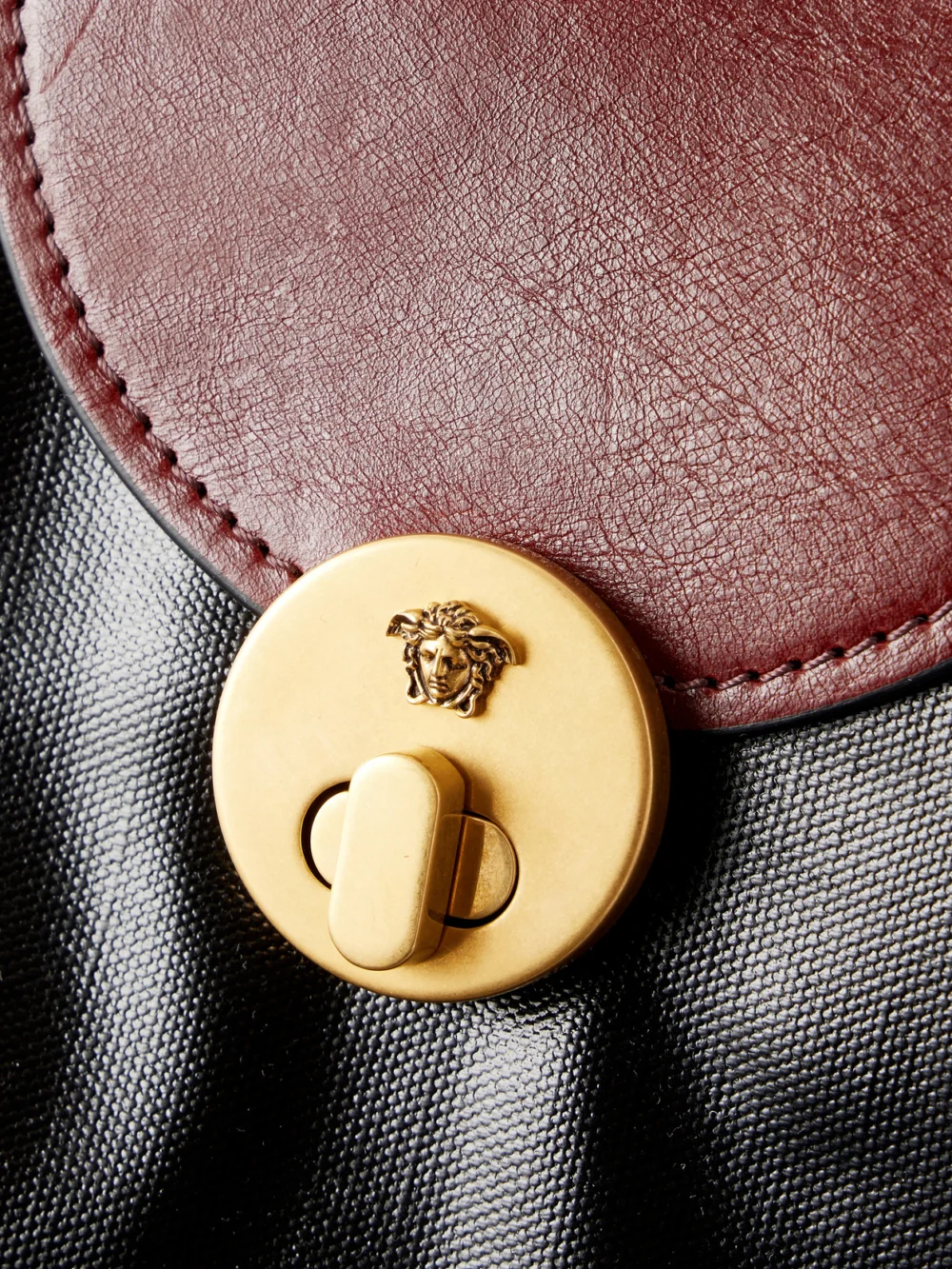 Close-up detail of the Versace Vivienne Medusa-embellished Leather-trimmed Coated Canvas Tote