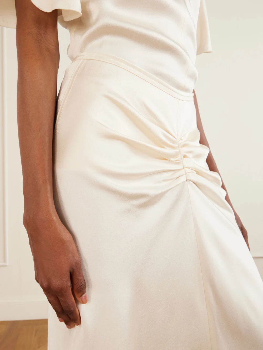 Close-up detail of the Victoria Beckham Bela Ruched Satin Midi Skirt
