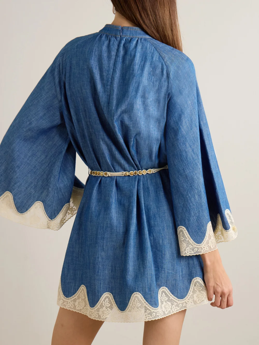 Back view of the Zimmermann Awaken Belted Lace-trimmed Denim Mini Dress