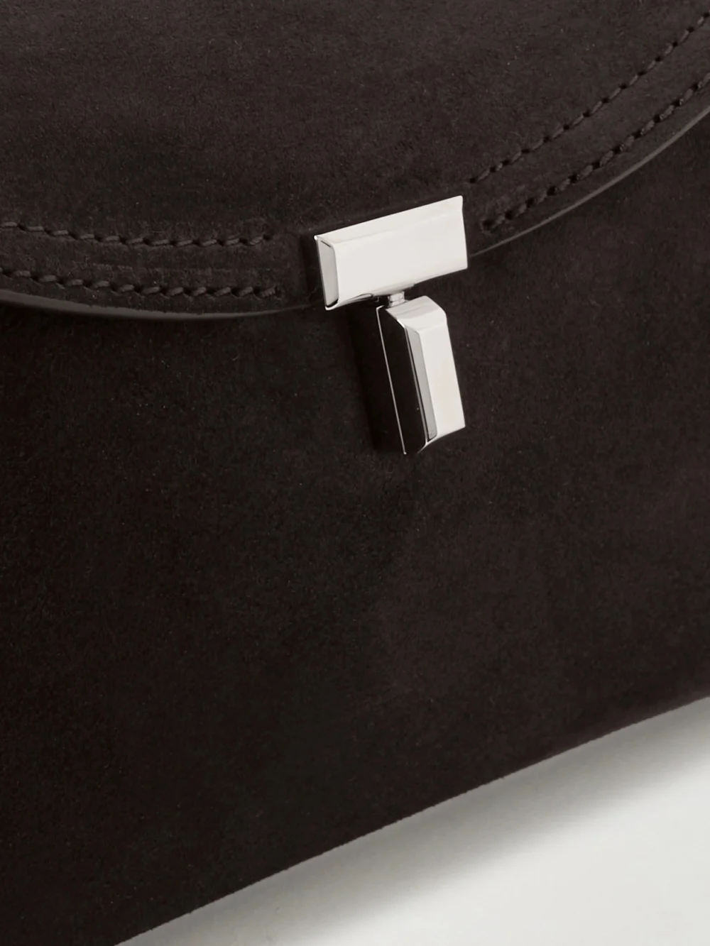 Close-up detail of the Totême T-lock Suede Clutch