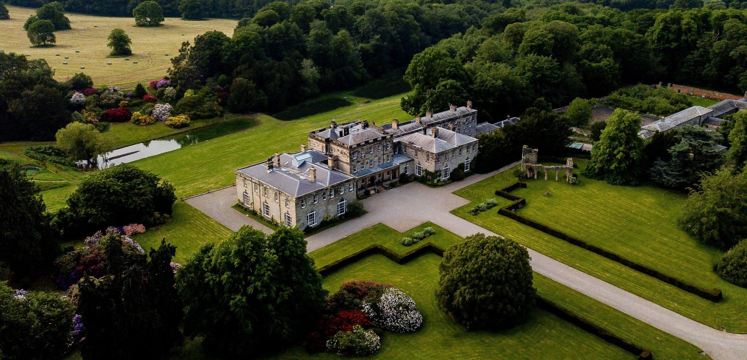 Aerial view of the house, its formal lawns and hedges, the lake and the parkland beyond, Birdsall House