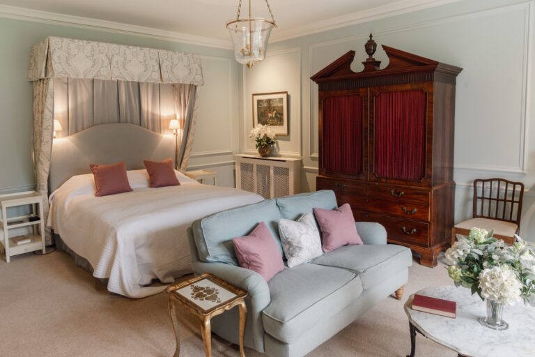 A pale blue bedroom with a canopied bed, a blue sofa and a mahogany linen press, Birdsall House