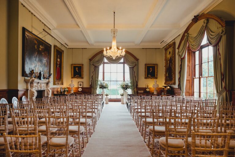 The Dining Room set for a ceremony, with rows of gold chairs either side of a white aisle and a chandelier overhead, Birdsall House