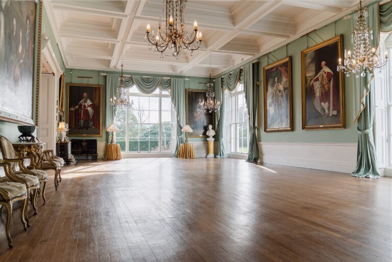 The empty Ballroom with its coffered ceiling, chandeliers, green walls and family portraits, Birdsall House