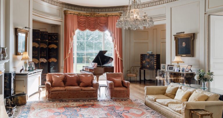 The Oval Room with its grand piano, salmon-pink drapes, sofas and family pictures, Birdsall House
