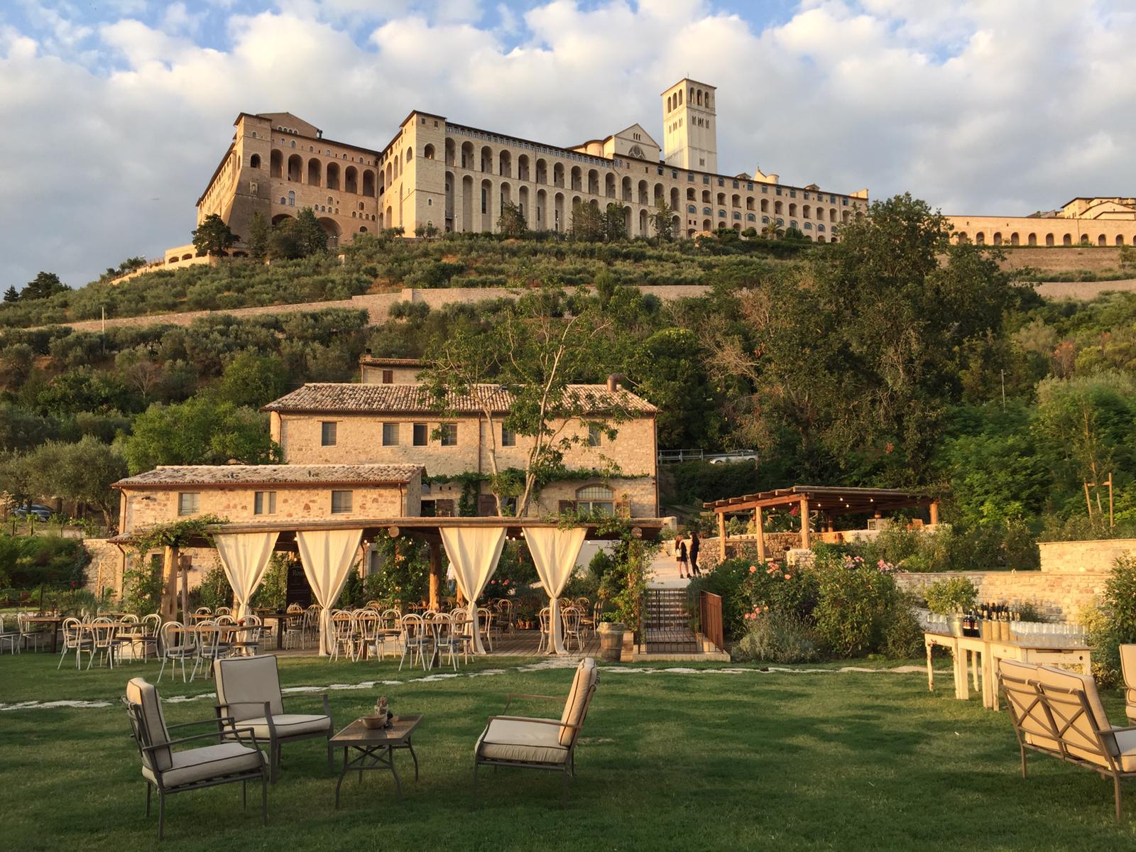 The stone buildings of the borgo and its lawn, with the Basilica of San Francesco on the hill above, Borgo Antichi Orti Assisi